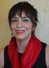 A woman with short hair, wearing a red scarf and a black top, poses for the photo.
