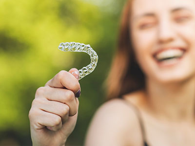 The image features a person holding up an object that resembles a toothbrush with bristles, which is likely meant to be a dental appliance or tool.